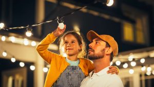 A young girl installing a light bulb with her father